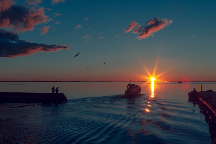 Boat sailing on the sea at sunset with clouds