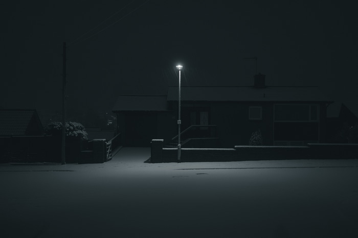 A house at night with a street light in the snow