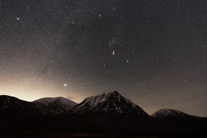 Starry night sky over snow-capped mountains