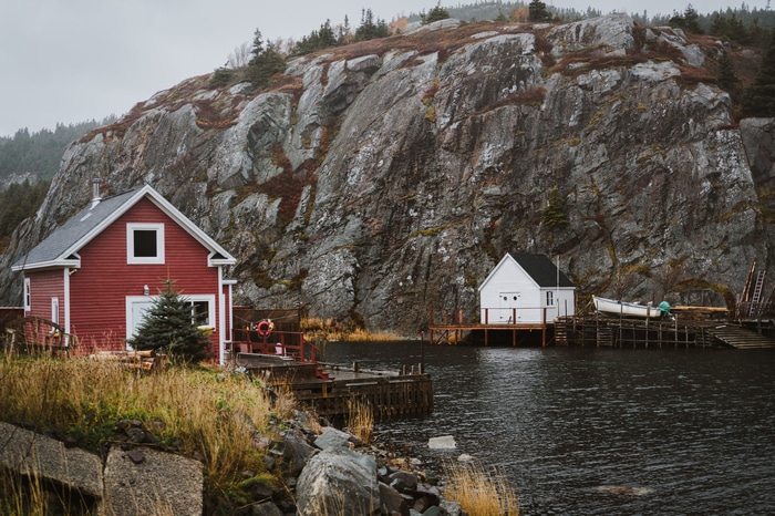 Red and white houses by a rocky cliff and water