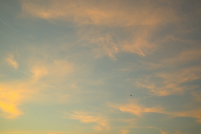 Airplane flying in a cloudy sky at sunset