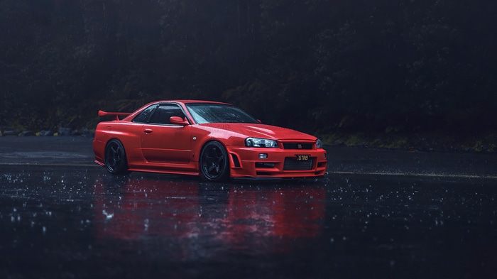 Red Nissan Skyline R34 on a wet road