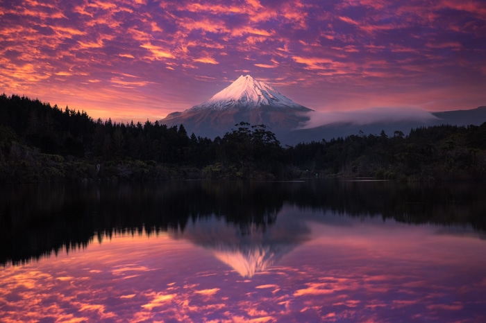 Mount Taranaki reflected in a lake at sunset