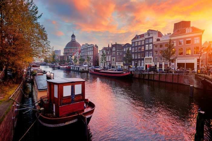 Amsterdam canal at sunset with houseboats and buildings