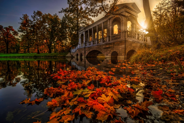 Marble Arch Bridge over water with autumn leaves and sun rays