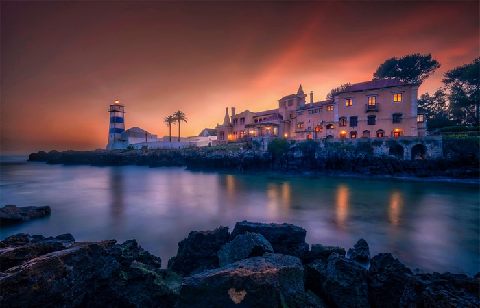 Lighthouse and building by the sea at sunset