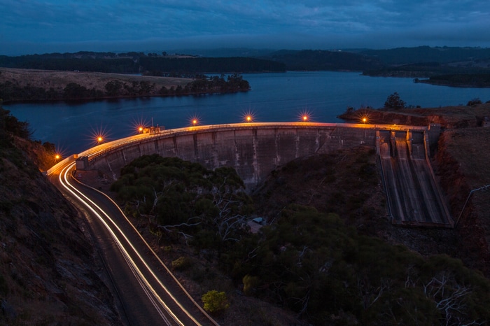 Dam at night with car light trails and reservoir