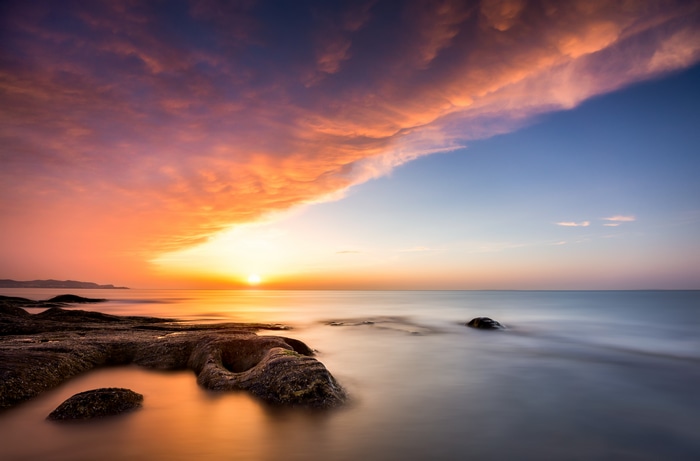 4K sunset over the sea with rocky shore