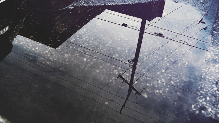 Reflection of utility pole and wires in a puddle