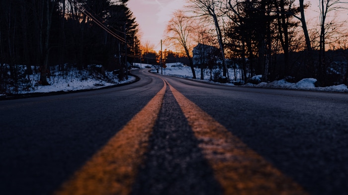 Road with double yellow lines at dusk with snow