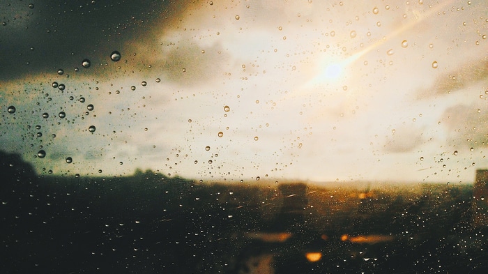 Raindrops on a window with sun and clouds