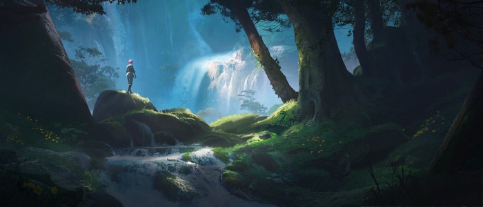 A person stands on a rock overlooking a waterfall in a forest.