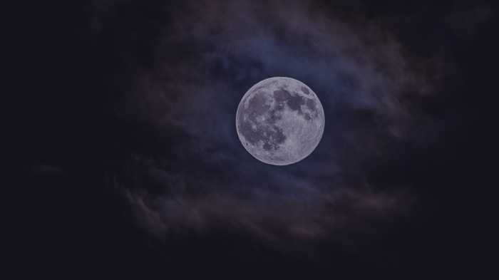 Full moon in the night sky with clouds