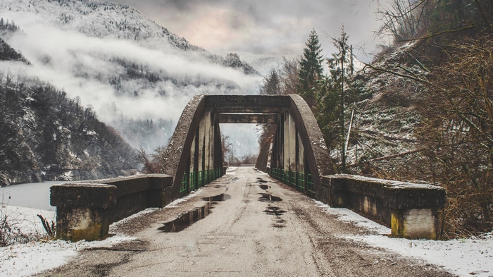 4K winter bridge over a misty mountain landscape