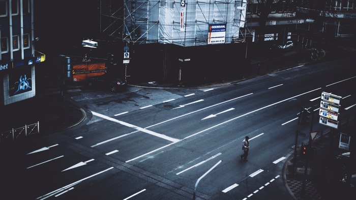 Man crosses a dark, empty street at night