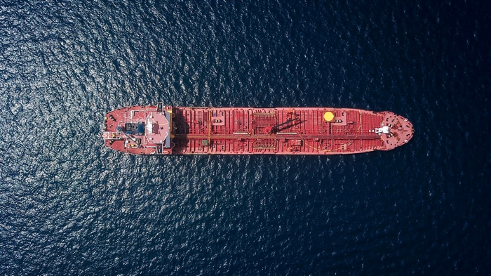 4K aerial view of a red cargo ship on the sea
