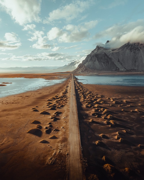 Road through sand dunes to mountains and lake