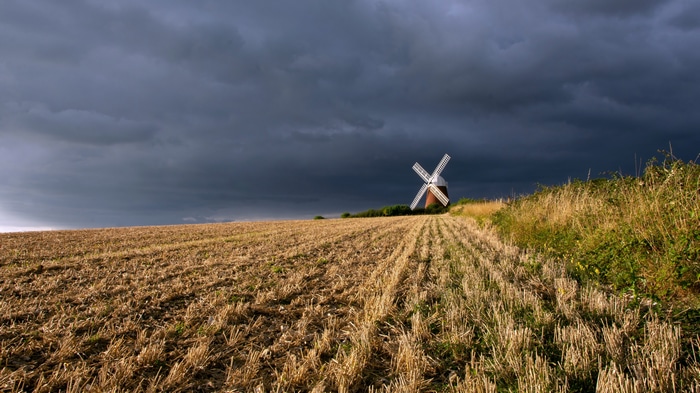 Windmill in a field under stormy clouds