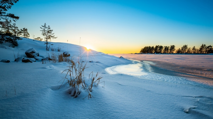 Winter landscape with sun setting over frozen lake