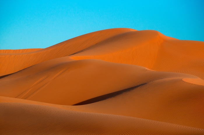 Desert sand dunes under a clear blue sky