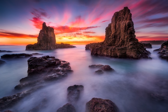 Ocean rocks at sunrise with orange and pink sky
