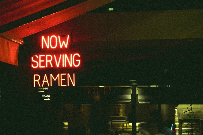 Neon sign saying "Now Serving Ramen"