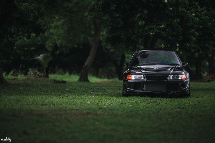 Black Mitsubishi Lancer Evolution VI parked on grass