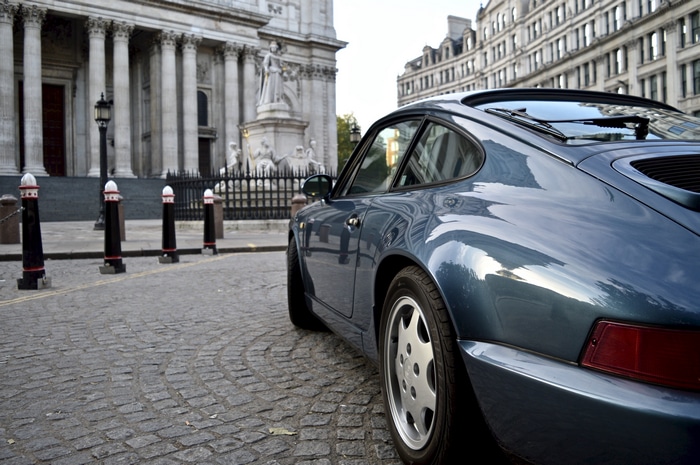 Porsche 964 parked on a cobblestone street in Europe