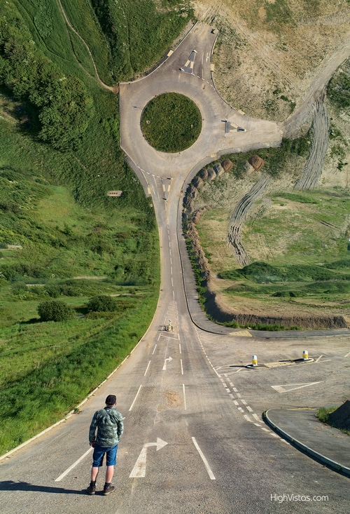Man standing on a surreal road with a roundabout
