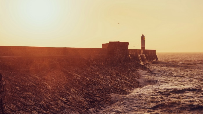4K lighthouse on a rocky coast at sunset