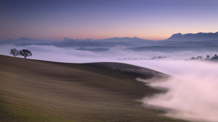 4K landscape of rolling hills with fog and mountains