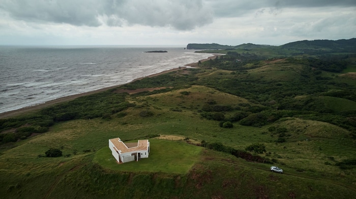 White house on green hills overlooking the sea