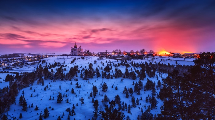 Winter village with church at sunset