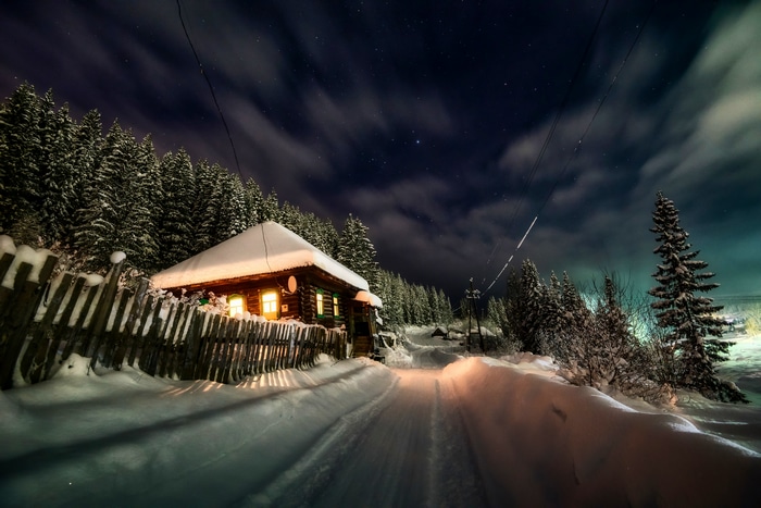 Snowy cabin at night with starry sky