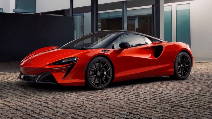 Red McLaren sports car parked on cobblestone