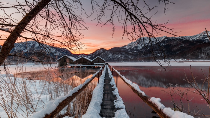 Winter sunset over a frozen lake with boathouses