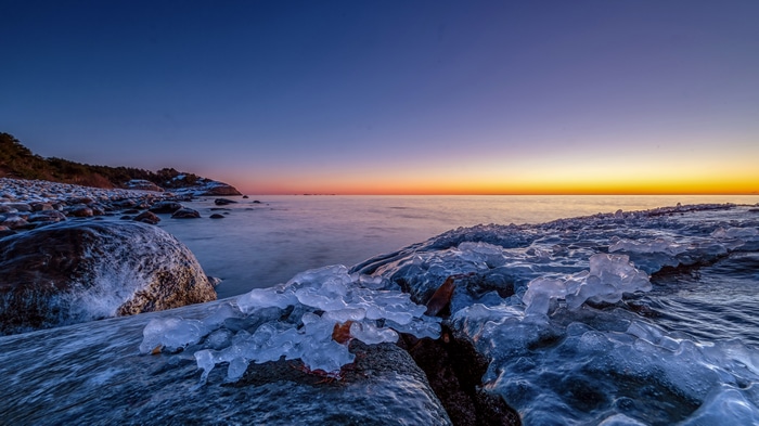 4K winter sunrise over a frozen rocky coast