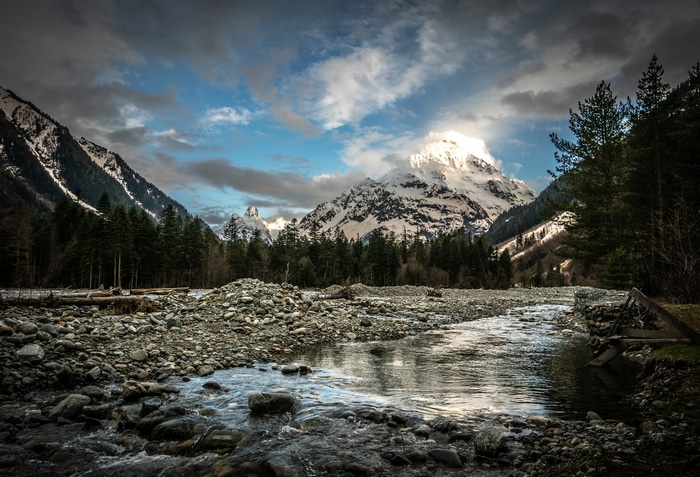 Snowy mountain range with river and forest in Karachay Cherkessia