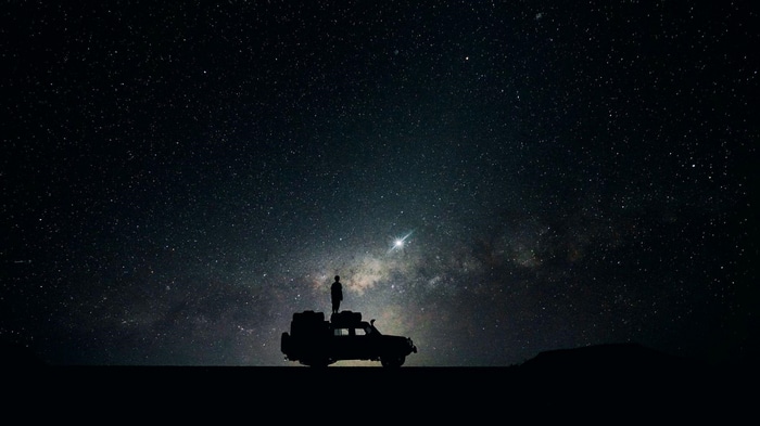 Silhouette of a person on a car under the night sky