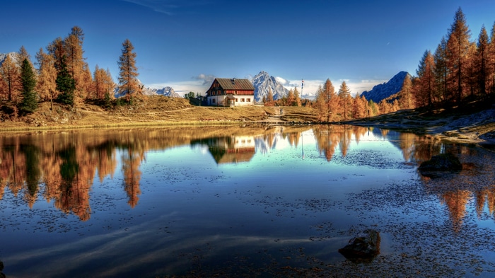 4K house on lake with autumn trees and mountains