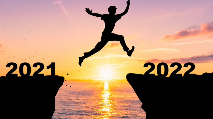 Silhouette of person jumping from 2021 to 2022 at sunset
