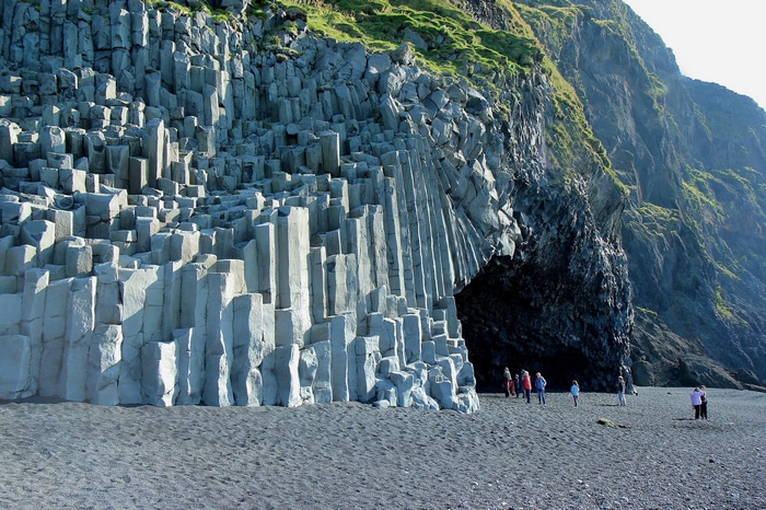 Basalt columns on a black sand beach with people