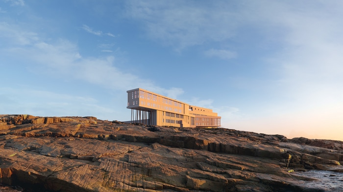 Modern building on rocky coast under blue sky