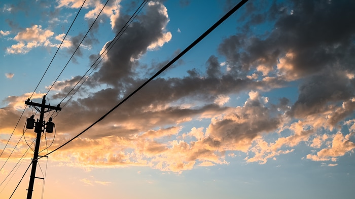 Power lines against a sunset sky with clouds in Texas