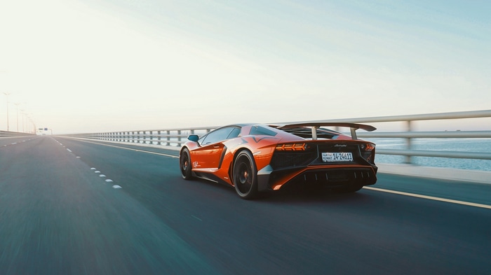 Orange Lamborghini Aventador driving on a highway
