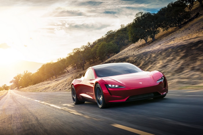 Red Tesla Roadster driving on a road