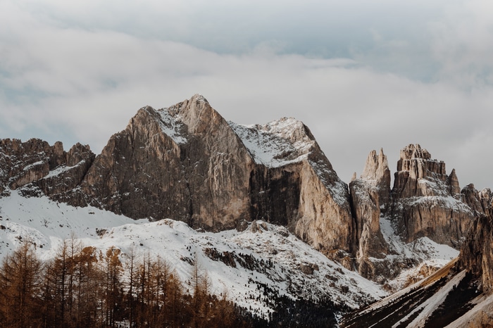 Snowy mountains and forest under cloudy sky