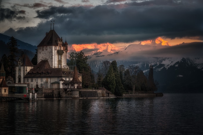 Castle Oberhofen on a lake with mountains at sunset