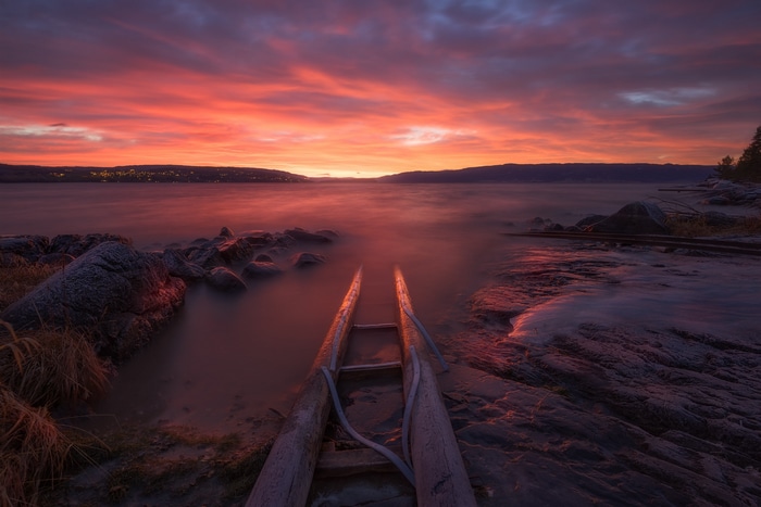 Sunset over a calm lake with a wooden boat ramp
