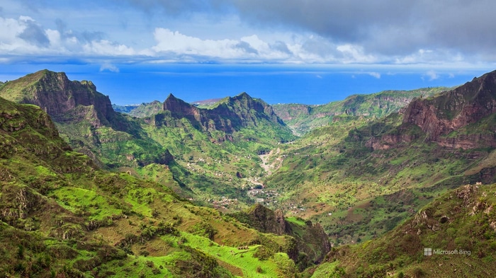 Green mountain valley with ocean in the background